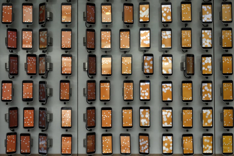 Smartphones hang on a wall at the Mobile World Congress (MWC), the world's biggest mobile fair, on February 28, 2018 in Barcelona.